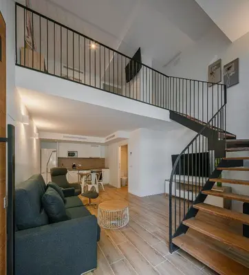 a living room with a couch and a staircase at NEW DUPLEX, 2 WC, FRENTE CIUDAD DE LAS CIENCIAS Y LAS ARTES in Valencia