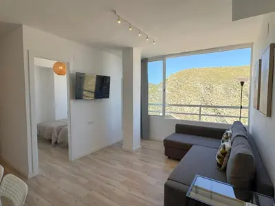 a living room with a couch and a large window at NUEVO, primera linea de playa, con piscina y vistas al mar in Cullera