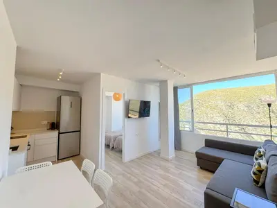 a kitchen and living room with a couch and a table at NUEVO, primera linea de playa, con piscina y vistas al mar in Cullera