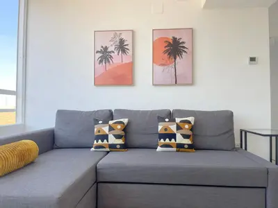 a gray couch with pillows in a living room at NUEVO, primera linea de playa, con piscina y vistas al mar in Cullera