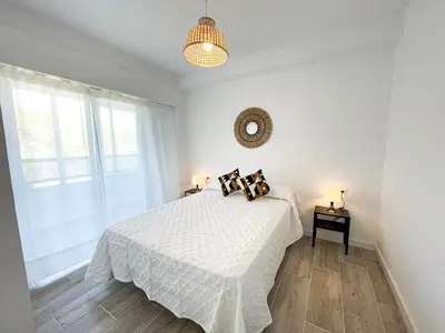 a white bedroom with a bed and a window at NUEVO, primera linea de playa, con piscina y vistas al mar in Cullera