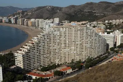 a large building next to a beach with buildings at NUEVO, primera linea de playa, con piscina y vistas al mar in Cullera