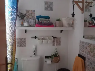 a bathroom with a toilet and shelves on the wall at Casita Mona y Acogedora in Alaquas