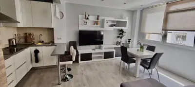 a kitchen with white cabinets and a table with chairs at Cosy and Modern Puerto de Sagunto Holiday Flat in Puerto de Sagunto