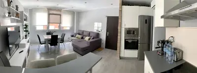 a kitchen and living room with a couch and a table at Cosy and Modern Puerto de Sagunto Holiday Flat in Puerto de Sagunto