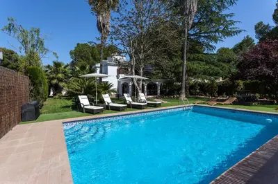 a swimming pool with chairs and a house at VILLA LATEL in Serra
