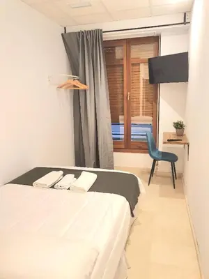 a bedroom with a bed and a chair and a window at PLAZA HOME ResEst in Valencia