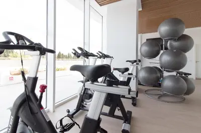 a gym with cardio equipment in a room with windows at Global Vacacional, Apartamento con terraza y vistas al mar y a la montaña in Canet de Berenguer