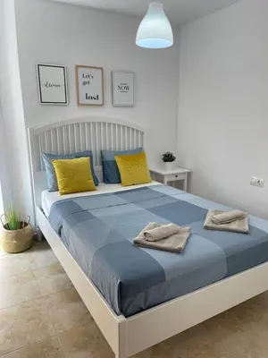 a bedroom with a large bed with yellow and blue pillows at UIM Mediterraneo Felipe 6 Wifi in Puerto de Sagunto