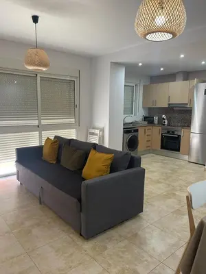 a living room with a couch and a kitchen at UIM Mediterraneo Felipe 6 Wifi in Puerto de Sagunto