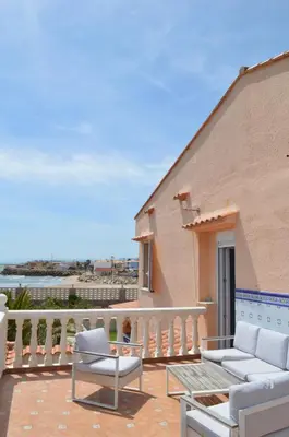 a patio with two chairs and a table on a balcony at Oasis en la playa: piscina y relax in Cullera