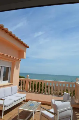 a balcony with a couch and chairs and the ocean at Oasis en la playa: piscina y relax in Cullera