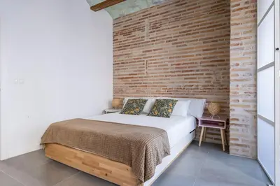 a bed in a room with a brick wall at Céntrica y encantadora vivienda. in Valencia