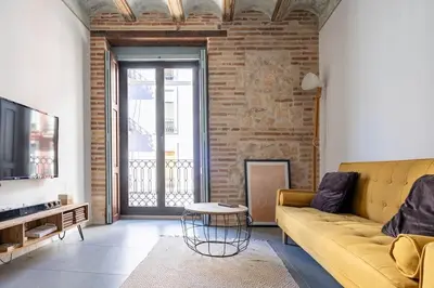 a living room with a yellow couch and a brick wall at Céntrica y encantadora vivienda. in Valencia