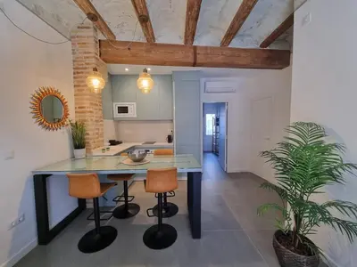a kitchen with a table and two stools at Céntrica y encantadora vivienda. in Valencia
