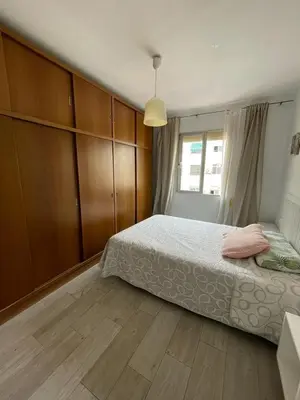 a bedroom with a bed and wooden cabinets at MALVARROSA BEACH FAMILIAR in Valencia