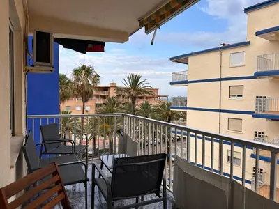 a balcony with chairs and a view of palm trees at Apartamento Tavernes Playa in Tavernes de Valldigna