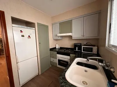 a kitchen with a white refrigerator and a sink at Apartamento Tavernes Playa in Tavernes de Valldigna