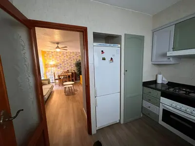a kitchen with a white refrigerator and a dining room at Apartamento Tavernes Playa in Tavernes de Valldigna