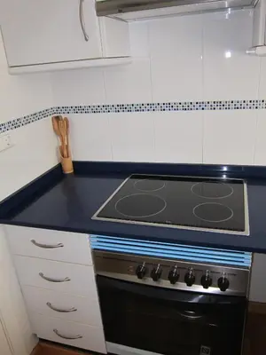 a kitchen with a black stove and white cabinets at Apartamentos Valencia in Valencia