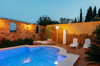 a swimming pool in front of a building with a stone wall at chalet, villa rodeada de naturaleza piscina a doce klm de Valencia y 7 del aeropuerto in Valencia