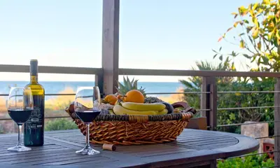 a basket of fruit and a bottle of wine on a table at Casa Catinca Cullera - Beach House On the Dune in Cullera