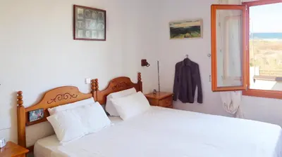 a bedroom with a bed with white sheets and a window at Casa Catinca Cullera - Beach House On the Dune in Cullera