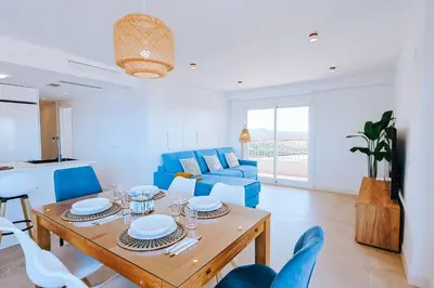 a living room with a table and blue chairs at Apartamento prémium con 5 Piscinas Barbacoa Tenis Frontenis in Mareny Blau