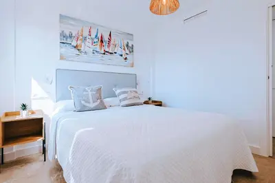a white bedroom with a white bed and a chandelier at Apartamento prémium con 5 Piscinas Barbacoa Tenis Frontenis in Mareny Blau