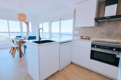 a kitchen with white cabinets and a sink and a table at Apartamento prémium con 5 Piscinas Barbacoa Tenis Frontenis in Mareny Blau