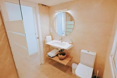 a bathroom with a sink and a toilet and a mirror at Apartamento prémium con 5 Piscinas Barbacoa Tenis Frontenis in Mareny Blau