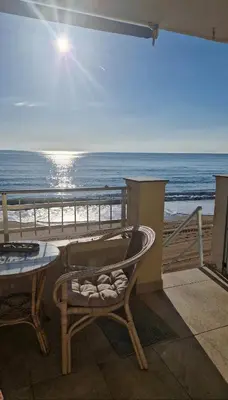 a table and a chair on a balcony overlooking the beach at Apartmán pri mori in El Brosquil