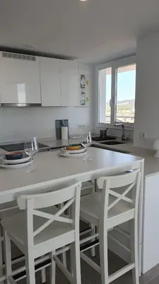 a kitchen with two white stools and a white counter top at Apartamento con vistas en Gran Canet in Canet de Berenguer