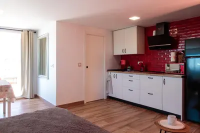 a kitchen with white cabinets and a red brick wall at Precioso ático en Valencia. in Valencia