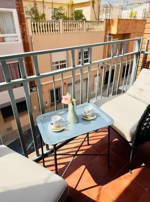 a table with a vase of flowers on a balcony at Playa Bonita Apartment in Puerto de Sagunto