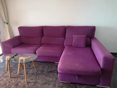 a purple couch in a living room with a table at Mi playa in Puerto de Sagunto