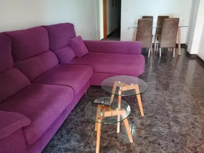 a purple couch in a living room with a glass table at Mi playa in Puerto de Sagunto