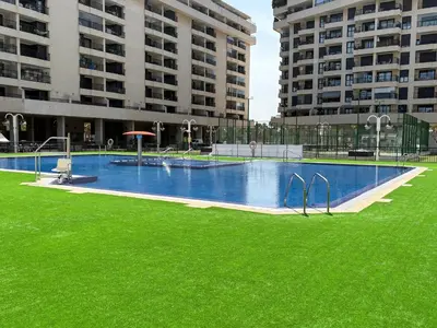 a large swimming pool with green grass and tall buildings at Valencia Beach Home 23 in Valencia