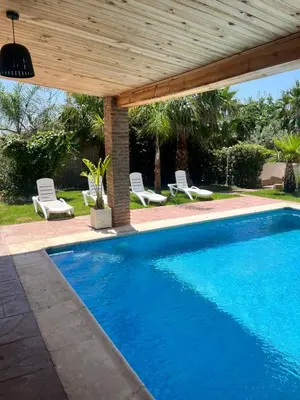 a swimming pool under a wooden pergola at Villas de descanso in Vilamarxant