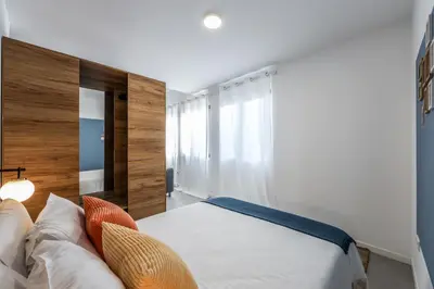 a bedroom with a bed and a mirror and a chair at AmazINN Places Valencia Cabanyal in Valencia