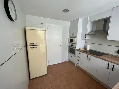 a kitchen with a refrigerator and a clock on the wall at Apartamento familiar en Cullera - Playa el Racó in Cullera