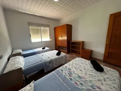 a bedroom with three beds and a dresser and a window at Casa Con Piscina Privada Marenyet in Cullera