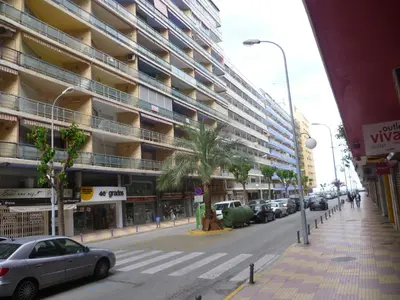 a street with cars parked in front of a large building at Torremar, D-13-25 in Cullera