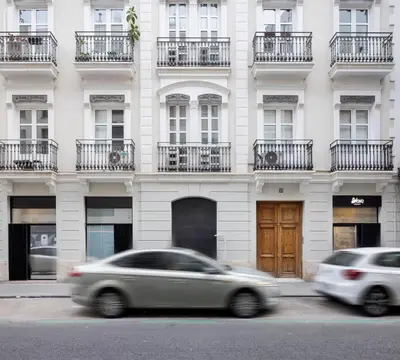 two cars speeding past a white building with balconies at Blanq Ruzafa in Valencia