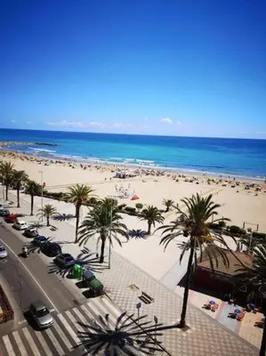 a beach with palm trees and a lot of people at Great 4 bedrooms apartament in Puerto de Sagunto - Full Apartment - 120m2 in Puerto de Sagunto