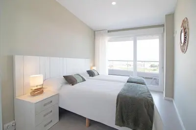 a white bedroom with a large bed and a window at Global Vacacional, Moderno apartamento con 2 terrazas y 3 habitaciones in Canet de Berenguer
