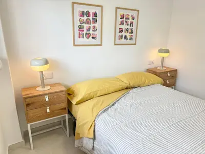 a bedroom with a bed and a nightstand and two lamps at Escápate al Sol Apartamento con Piscina y Playa Cercana in Playa Pobla de Farnals