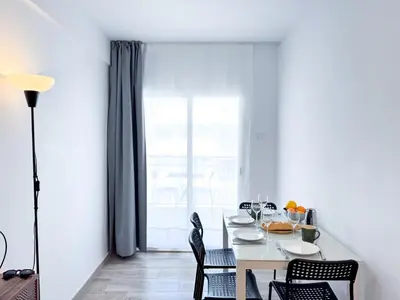 a white dining room with a table and chairs at NUEVO, a 50 metros de la playa y con vistas al mar in Cullera