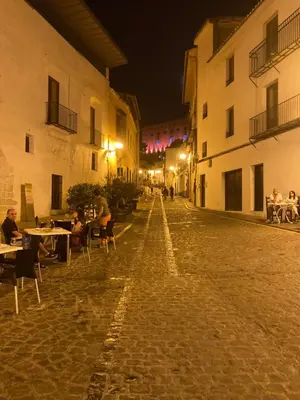 an empty street at night with people sitting at tables at Sagunto Castillo 17 in Sagunto