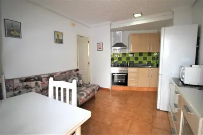 a kitchen and living room with a table and a couch at Sun & Sea Puebla in Puebla de Farnals